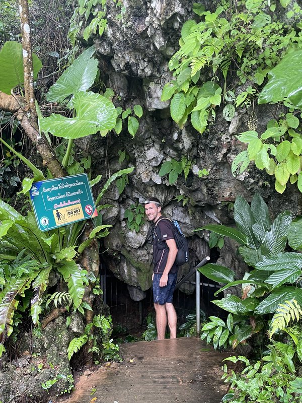 Steven Shonts at a cave entrance surrounded by lush tropical vegetation